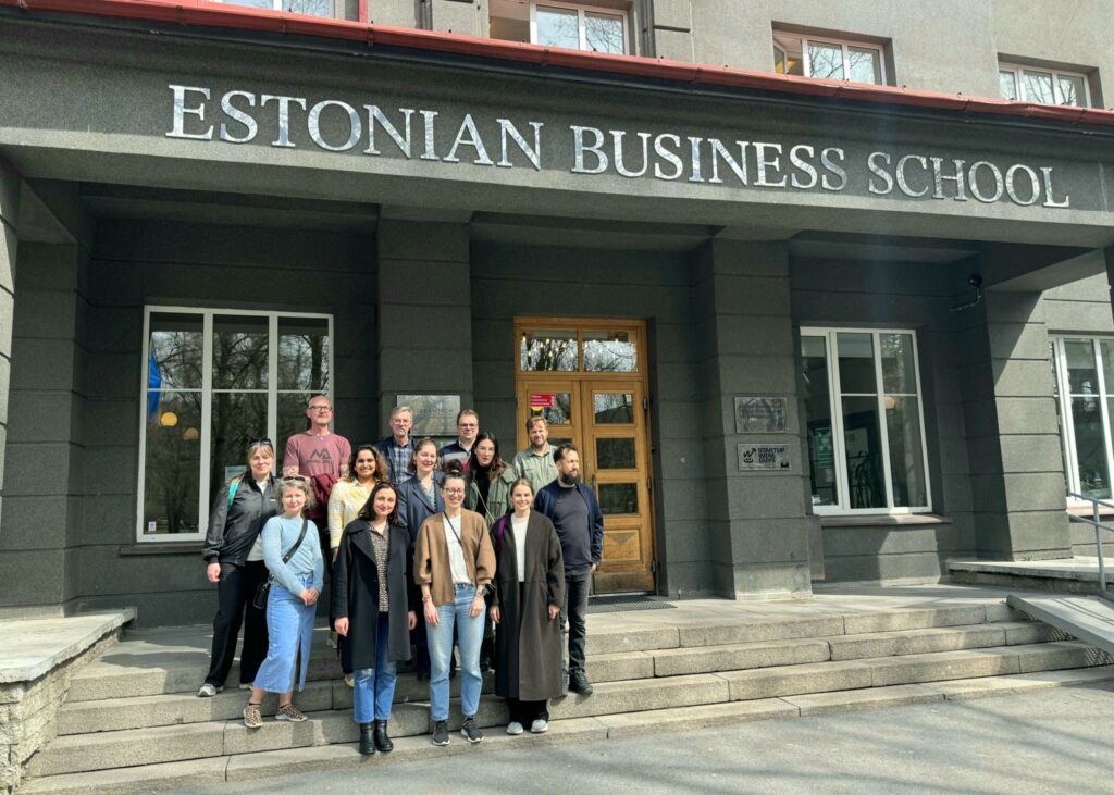 Network members, 13 people, in a group in front of Estonian business school entrance, on stone stairs.